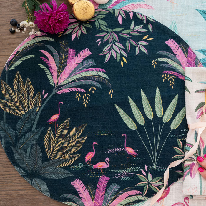 Round placemat with tropical leaf and flamingo design with a navy background.