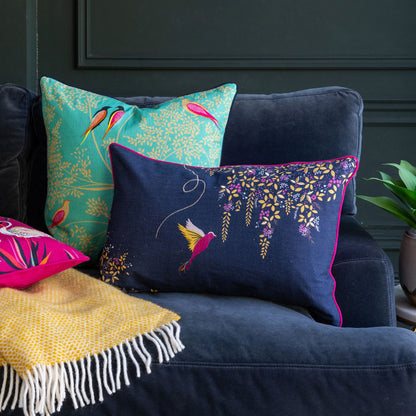 Navy hummingbird cushion on the sofa with two other cushions
