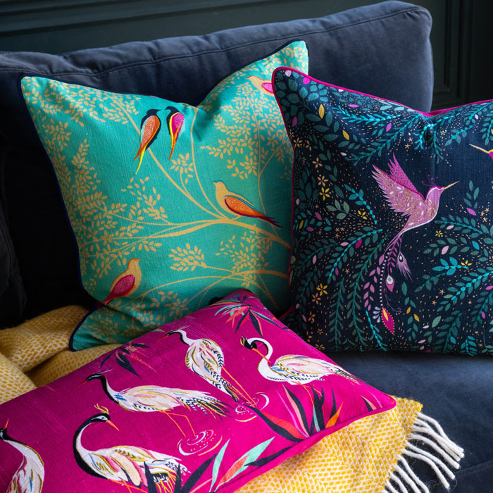 Green birds design cushion on the sofa with two other cushions.