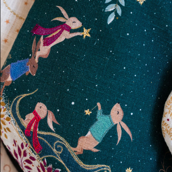 Christmas stocking with rabbits in sleigh design on dark green background.
