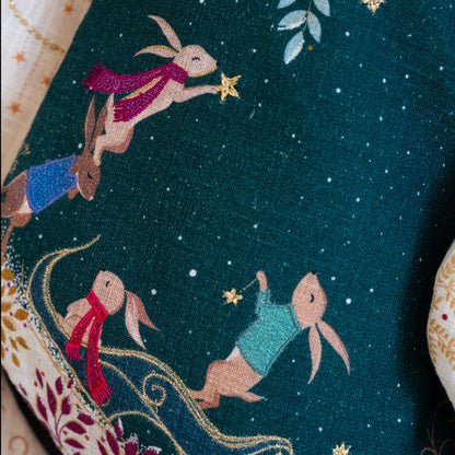 Christmas stocking with rabbits in sleigh design on dark green background.