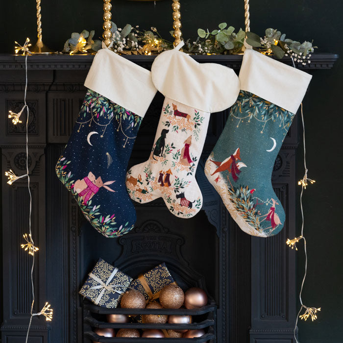 Three decorated Christmas stockings hanging above a fireplace with decorative items.