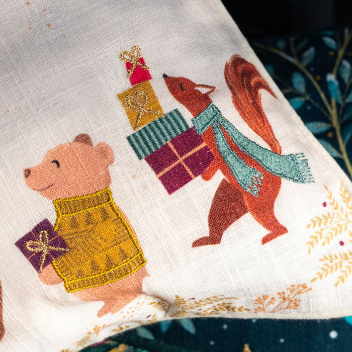 Embroidered design of a bear and a fox with presents on a fabric cushion