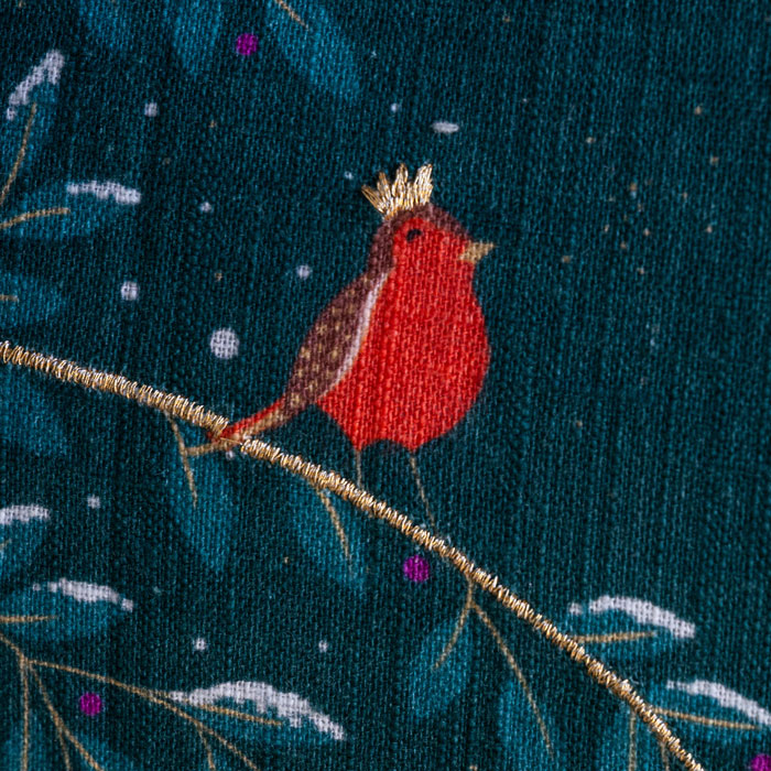 Close up of embroidered robin with a gold crown on a dark blue fabric cushion.