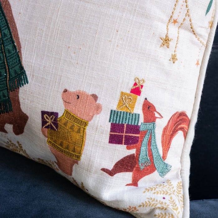 Decorative pillow with embroidered animals and gift boxes on a cream background
