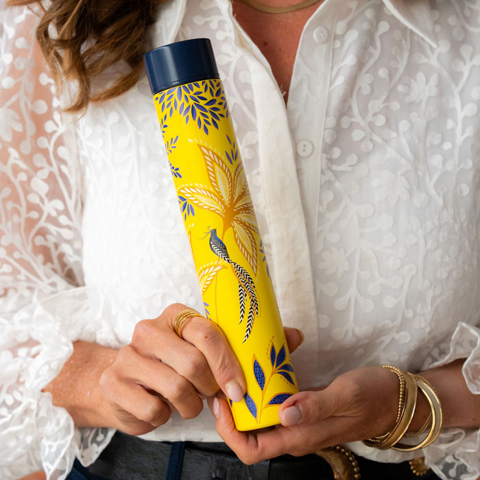 Someone holding yellow water bottle with botanic bloom design and gold detailing, can get an idea of the scale.