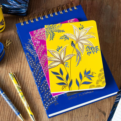 Yellow and pink notebooks stacked on top of our wiro daily planner, showing patterns and designs.