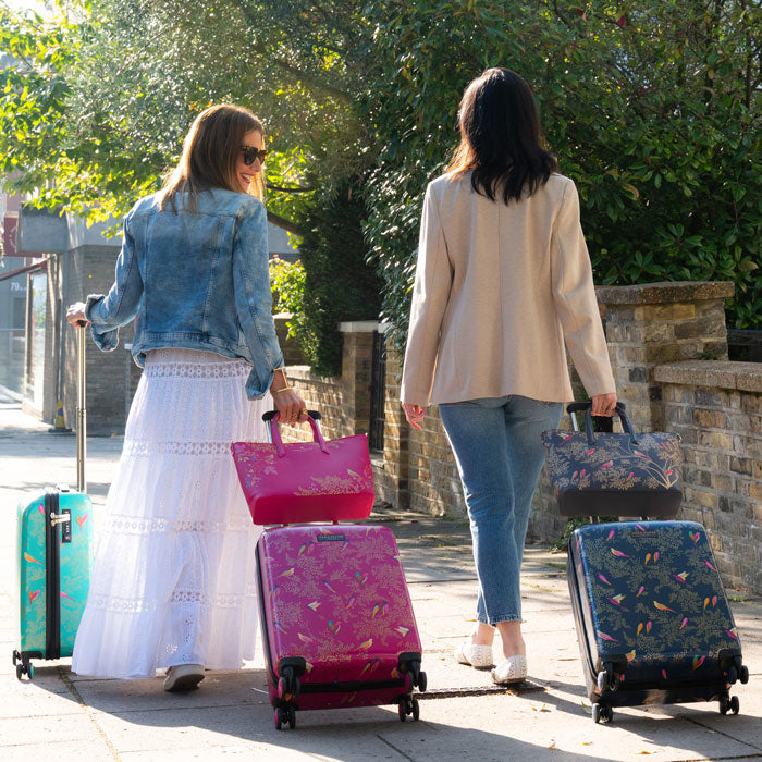 Two women walking with. the three cabin cases from the collection, and matching handbags.