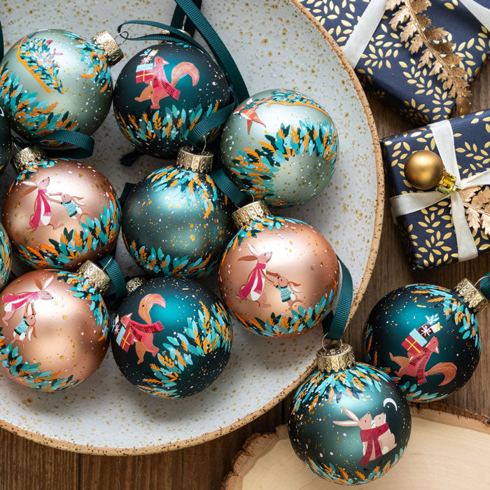 Decorative Christmas ornaments with artistic designs on a ceramic plate.