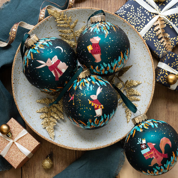 Decorative Christmas ornaments with animal illustrations on a plate, surrounded by gift boxes and ribbons.