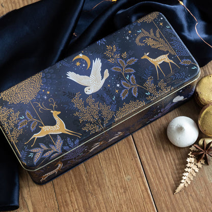 Decorative tin box with moonlit forest design on a wooden surface
