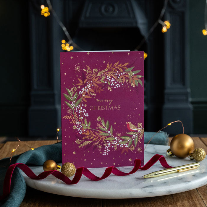 Purple Christmas card with festive design on a marble surface with decorative items.