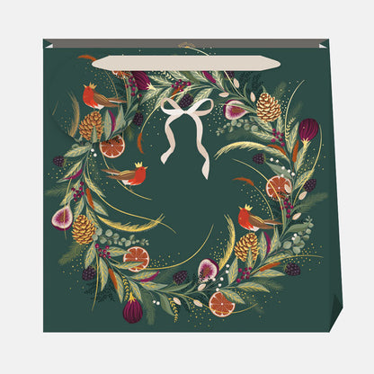 A dark green gift bag with traditional festive wreath design with robins and bow.
