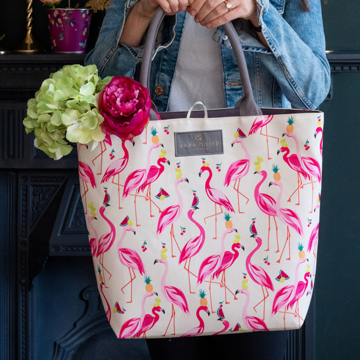 Flamingo print tote bag in shades of pink, on cream background with grey handles and interior.